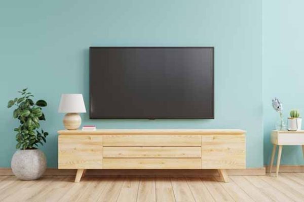 TV positioned above a wood console in a light blue room